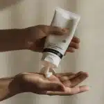 Mani che applicano crema idratante su pelle abbronzata