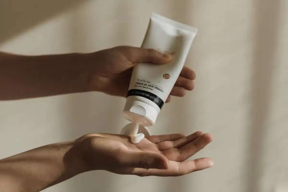 Mani che applicano crema idratante su pelle abbronzata