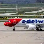 Pista aeroportuale avvolta da cenere vulcanica con aereo fermo sullo sfondo
