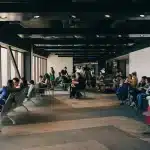 Passeggeri stanchi dormono su sedili e pavimenti in un terminal aeroportuale durante un'interruzione dei voli.