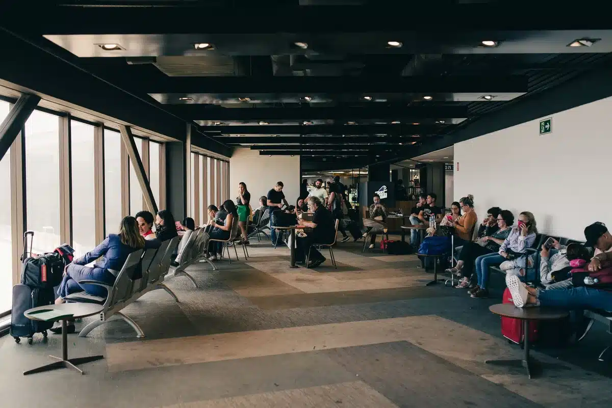 Passeggeri stanchi dormono su sedili e pavimenti in un terminal aeroportuale durante un'interruzione dei voli.