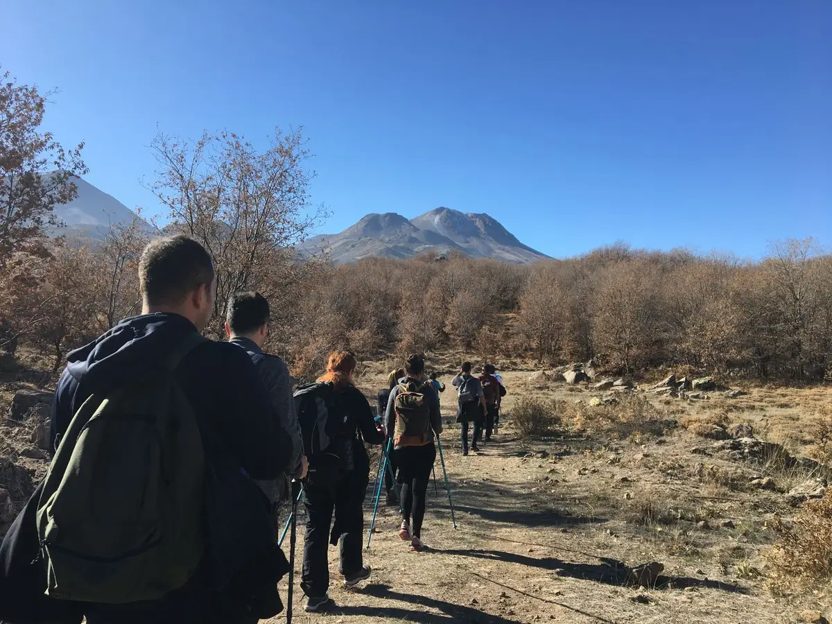 Gruppo di escursionisti su un sentiero alpino circondati da paesaggio autunnale