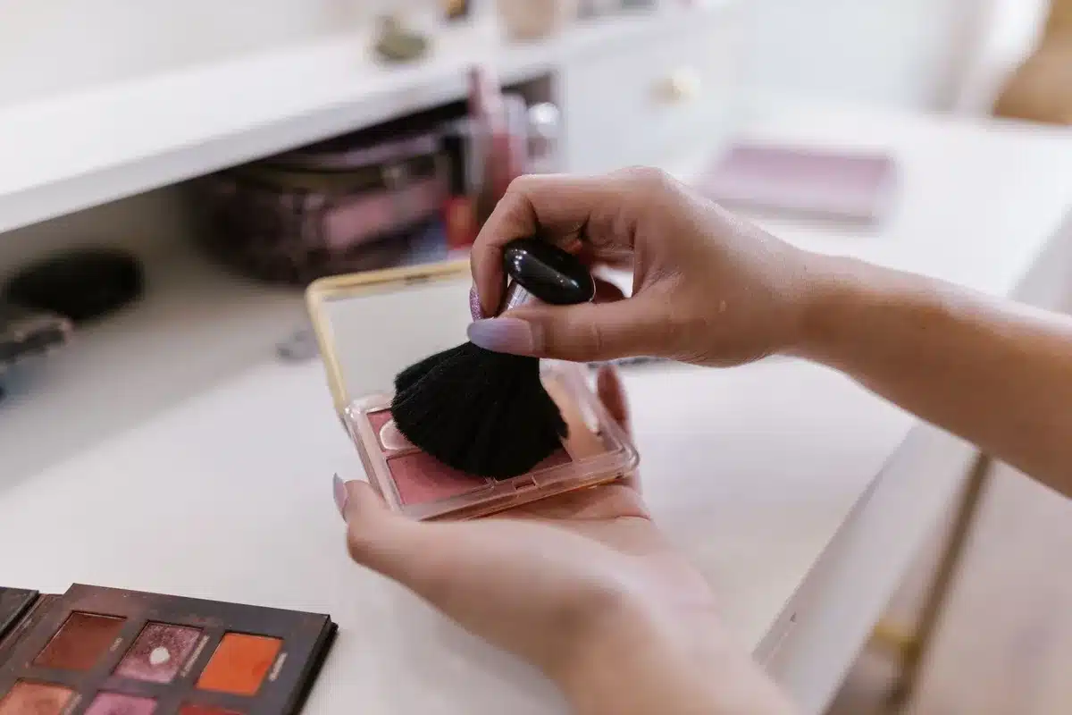 Applicazione di un blush cremoso che si assesta come polvere leggera su zigomi
