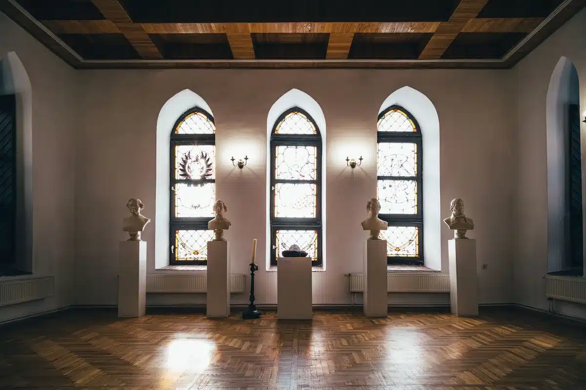 Interno di museo con opere d'arte esposte e visitatori che osservano le mostre