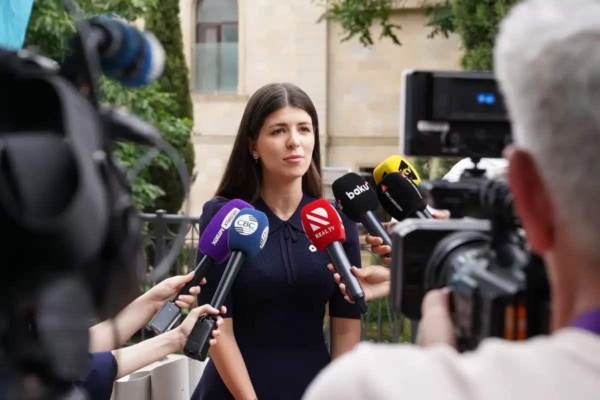Studio televisivo con giornalista al lavoro tra documenti e attrezzature di trasmissione