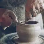 Mani che modellano argilla su una ruota da vasaio in uno studio artigianale illuminato dal sole