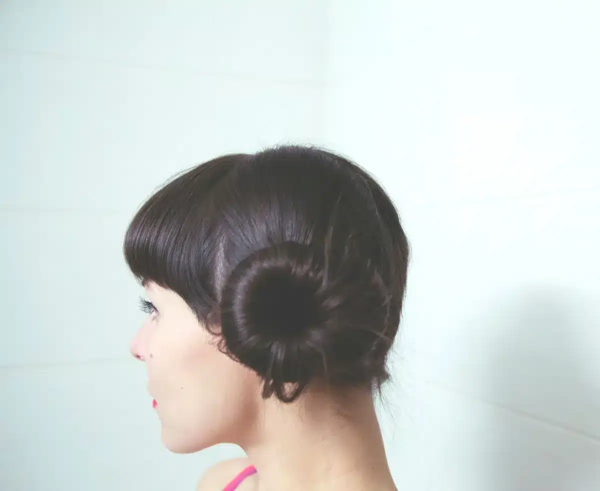 Mani che mostrano i passaggi per realizzare uno chignon basso morbido