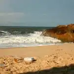 Spiaggia della Sardegna con teli verdi che coprono rifiuti emersi dall'erosione costiera