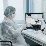 Tecnico di laboratorio manipola provette di conservazione di embrioni presso una postazione di embriologia