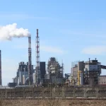 Stabilimento industriale con vigili del fuoco e fumo dopo un'esplosione