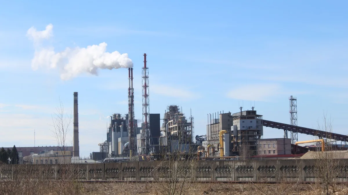 Stabilimento industriale con vigili del fuoco e fumo dopo un'esplosione