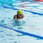 Nuotatrice in azione durante una gara di dorso in piscina olimpionica