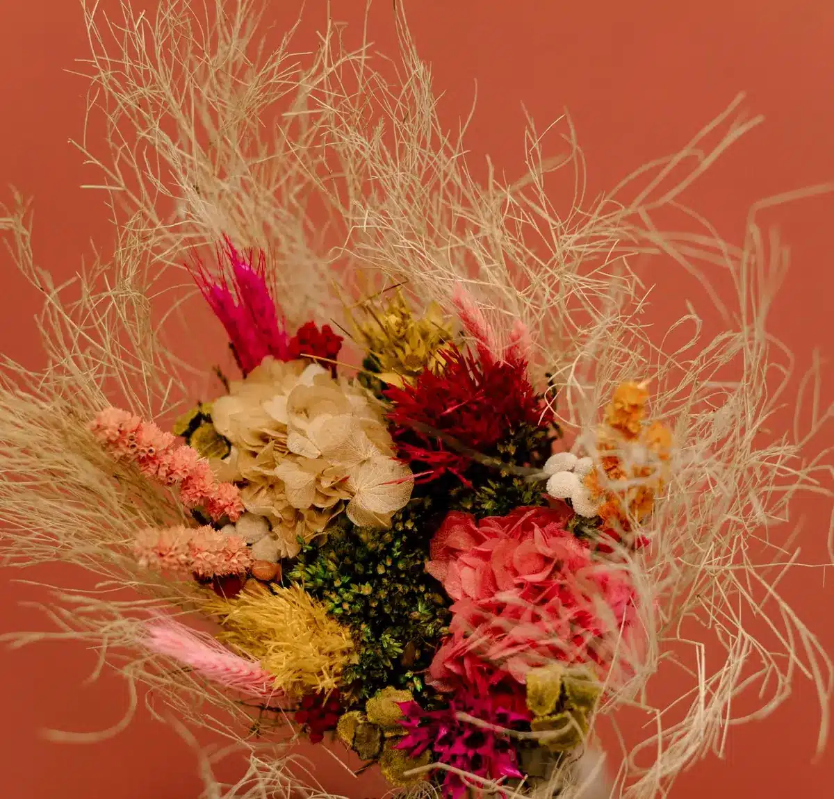 Bouquet di fiori di campo con garofani, margherite e rose in tonalità arancioni.