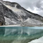 Pianoforte in un paesaggio alpino con lago e montagne sullo sfondo