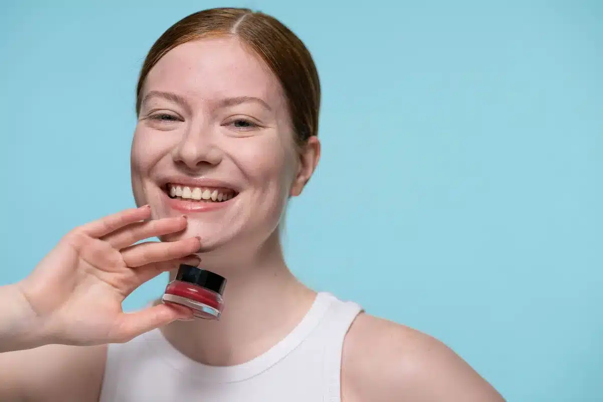 Applicazione di blush cremoso su pelle luminosa con texture naturale