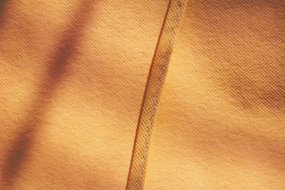 Gocce d'acqua su tessuto strappato con fibre sfibrate visibili