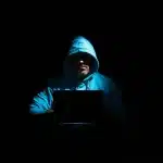 Persona che digita messaggi d'odio su uno smartphone in un ambiente buio