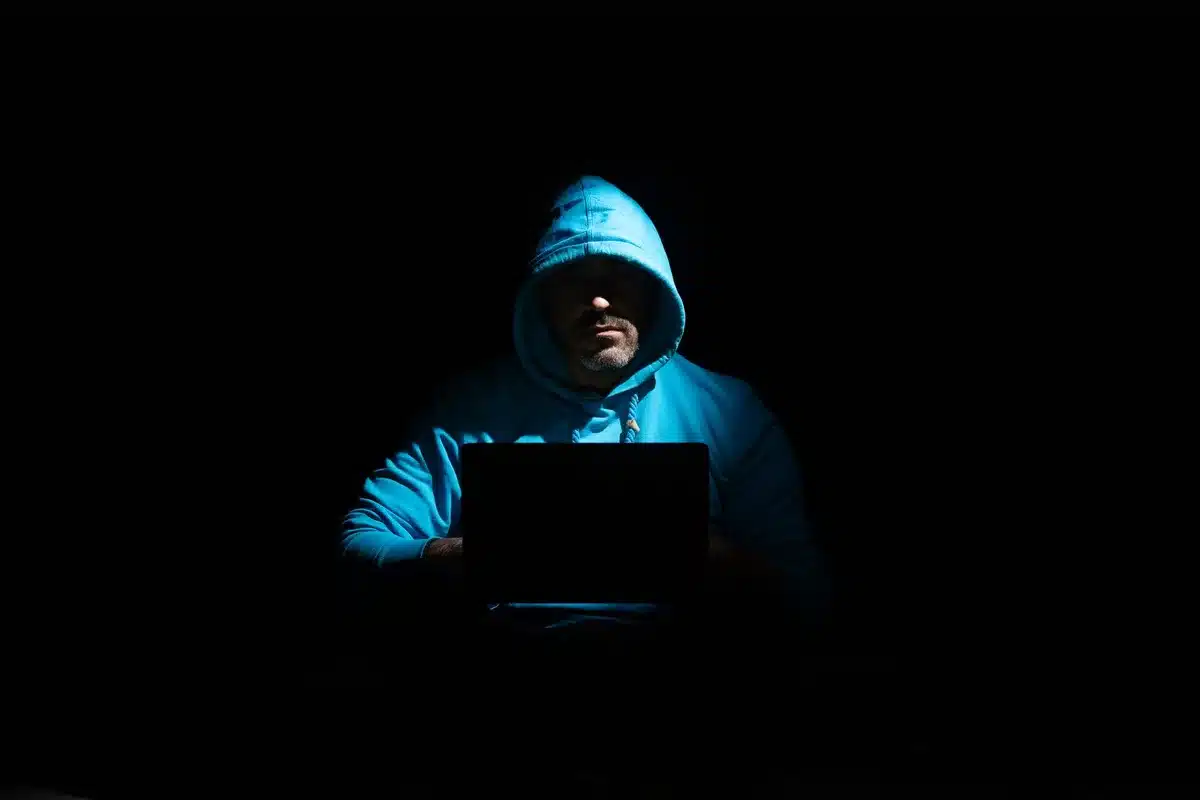Persona che digita messaggi d'odio su uno smartphone in un ambiente buio