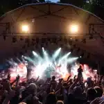 Giovani cantanti si esibiscono su un palco all'aperto durante una manifestazione musicale estiva in un parco.