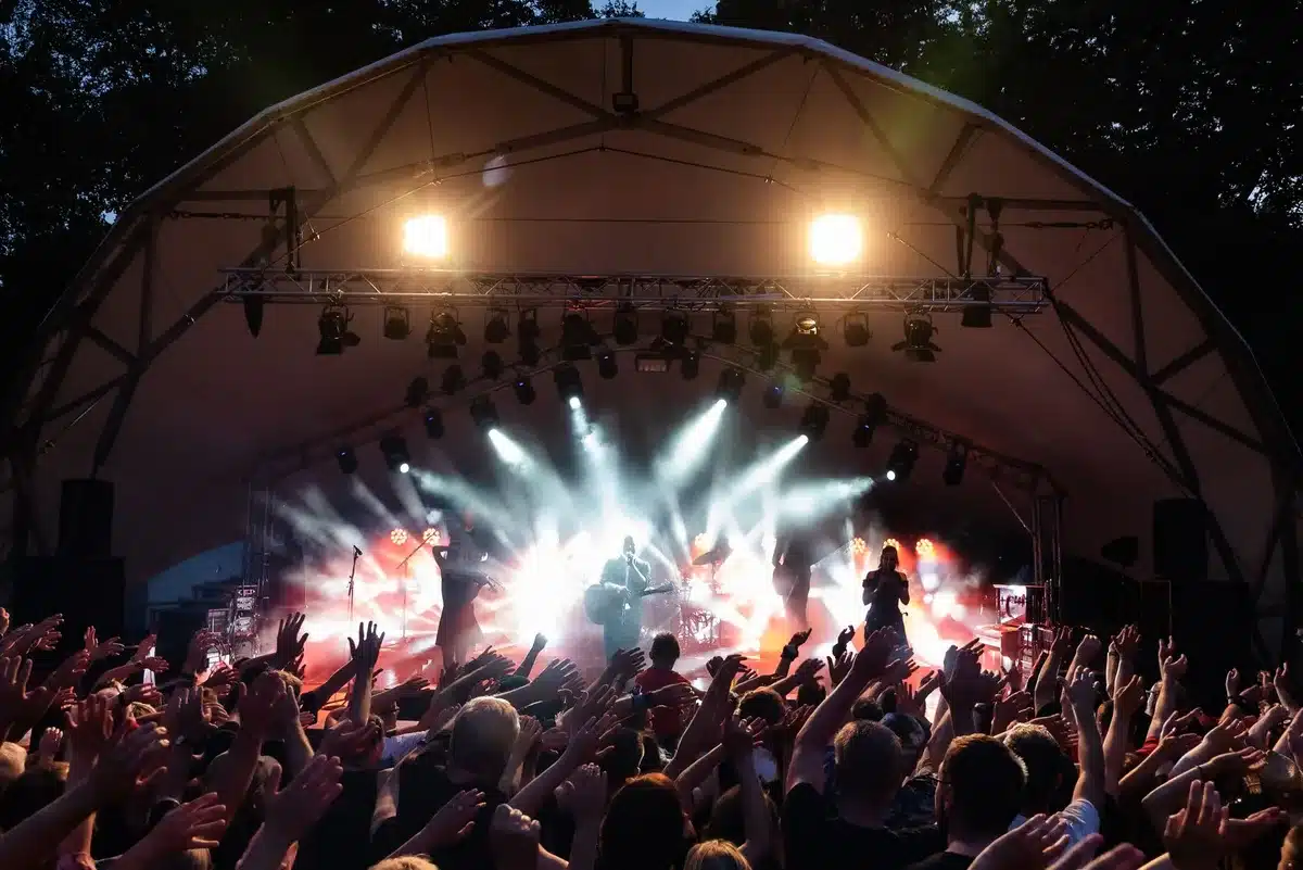 Giovani cantanti si esibiscono su un palco all'aperto durante una manifestazione musicale estiva in un parco.