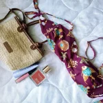 Borsa aperta con prodotti rinfrescanti estivi: spray termale, salviettine, ventilatore portatile e borraccia