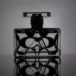 Bottiglie di profumo e body mist disposte su un tavolo con luci calde e oggetti in stile Y2K.