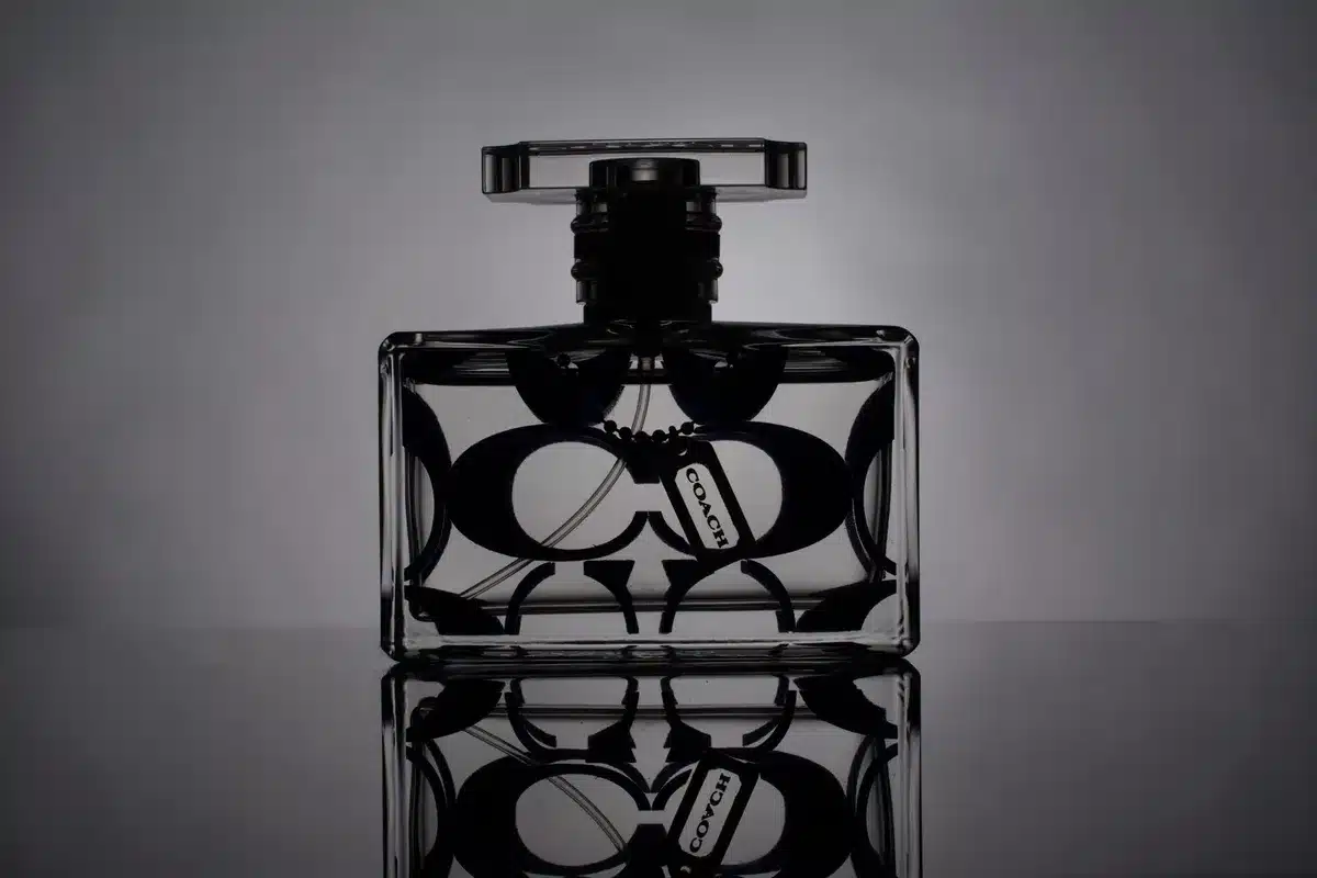 Bottiglie di profumo e body mist disposte su un tavolo con luci calde e oggetti in stile Y2K.