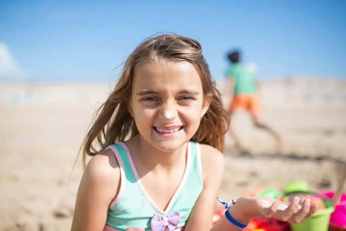 Bambino protetto con cappello e crema solare sulla spiaggia