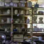 Migliaia di statuette di gatti in ceramica, legno e vetro disposte su scaffali e tavoli in una sala rustica