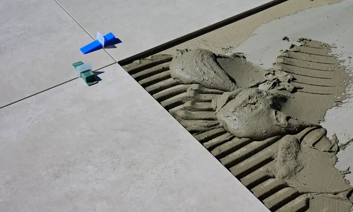 Mani che applicano stucco tra le piastrelle di pietra di una terrazza