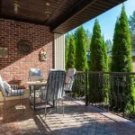 Mani che puliscono piastrelle di una terrazza con spazzola e acqua, superficie bagnata al sole