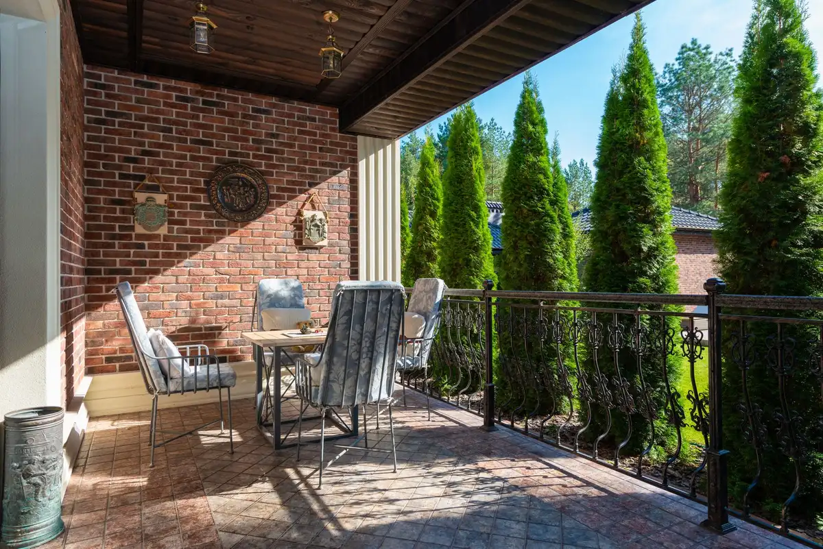 Mani che puliscono piastrelle di una terrazza con spazzola e acqua, superficie bagnata al sole