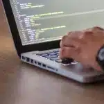 Schermo di computer con codice e metriche di ad server visibili, scrivania di sviluppatore web