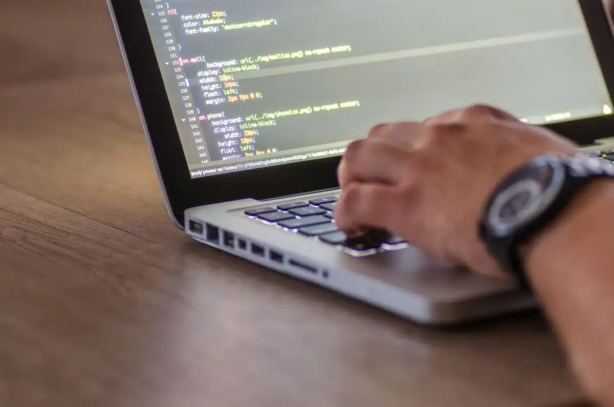 Schermo di computer con codice e metriche di ad server visibili, scrivania di sviluppatore web
