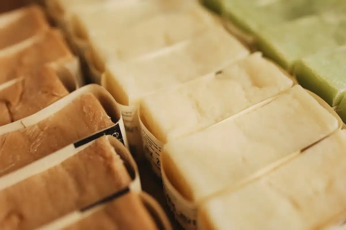 Diverse saponette artigianali con ingredienti naturali e packaging minimalista su superficie in legno.