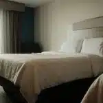 Camera d'hotel con tende chiuse, letto ordinato e cuscino, illuminazione soffusa per il riposo notturno