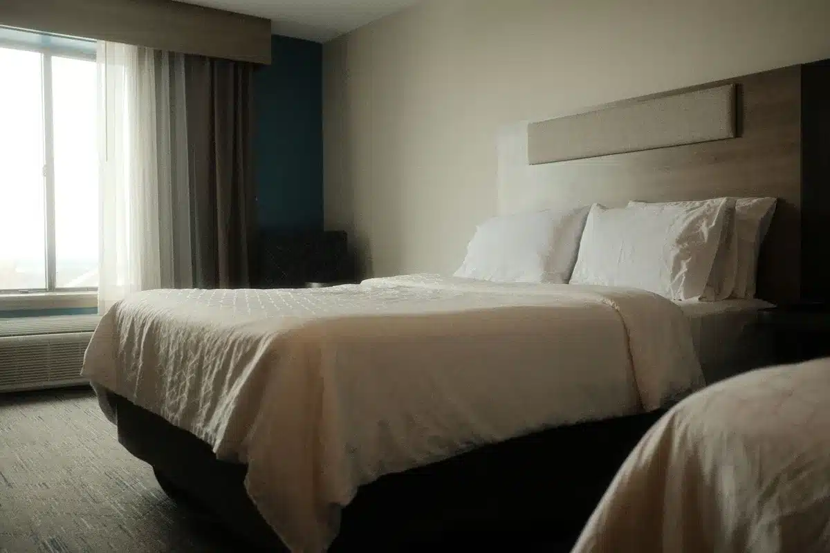 Camera d'hotel con tende chiuse, letto ordinato e cuscino, illuminazione soffusa per il riposo notturno
