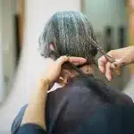 Parrucchiera che esegue un taglio a V sfumato su capelli lunghi con forbici professionali
