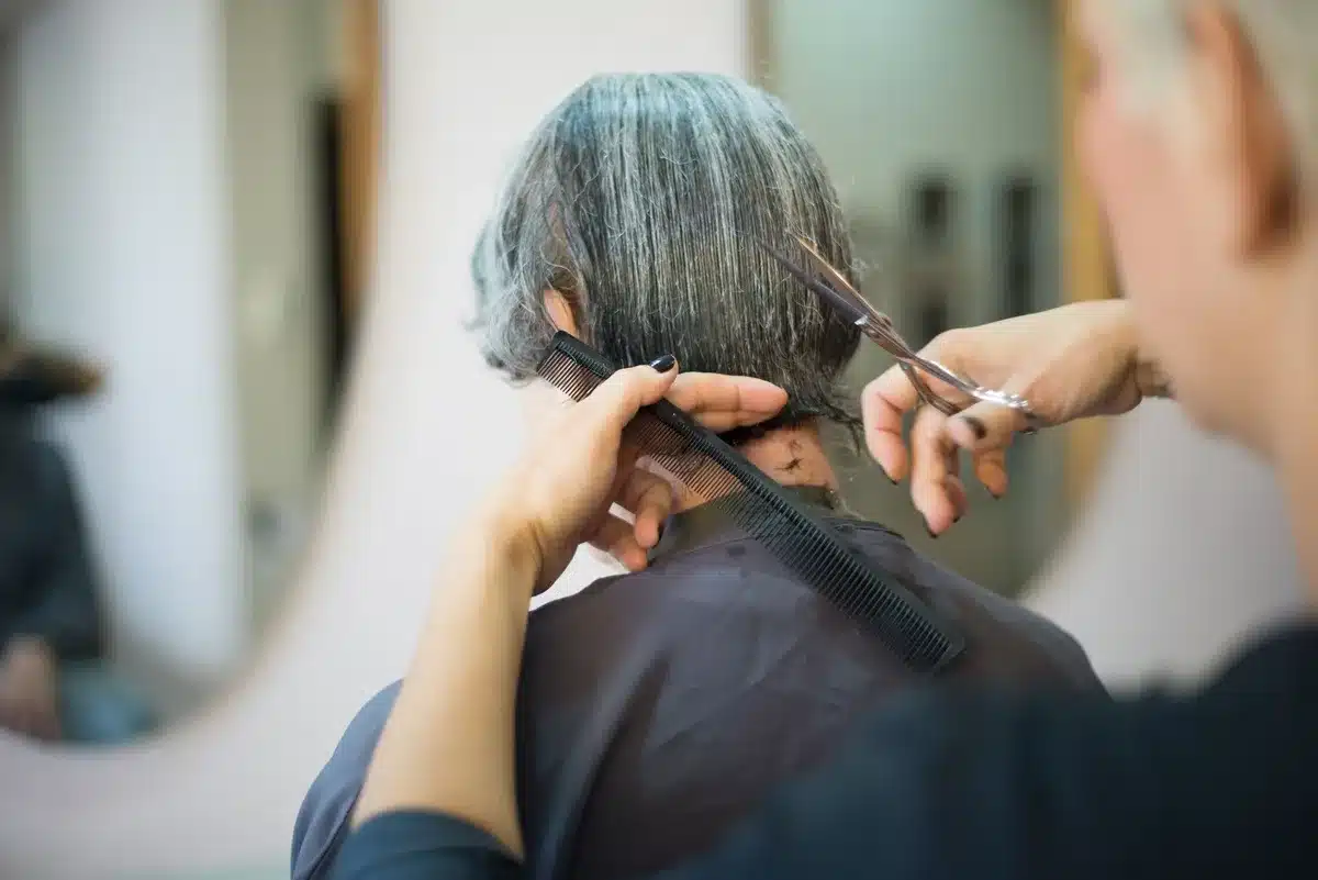 Parrucchiera che esegue un taglio a V sfumato su capelli lunghi con forbici professionali