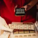 Cartelle d'archivio e negativi fotografici storici disposti su una scrivania, mani che manipolano documenti fragili sott