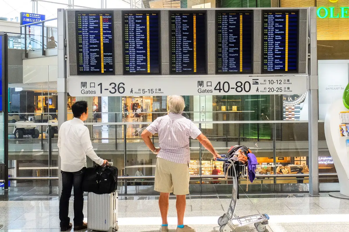 Viaggiatori in partenza presso una hall aeroportuale moderna con valigie, in un ambiente ordinato e sicuro.