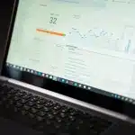 Scrivania di web designer con laptop aperto su dashboard di analytics e note tecniche