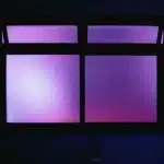 Interno minimalista con figura di spalle alla finestra, toni neutri e luce diffusa