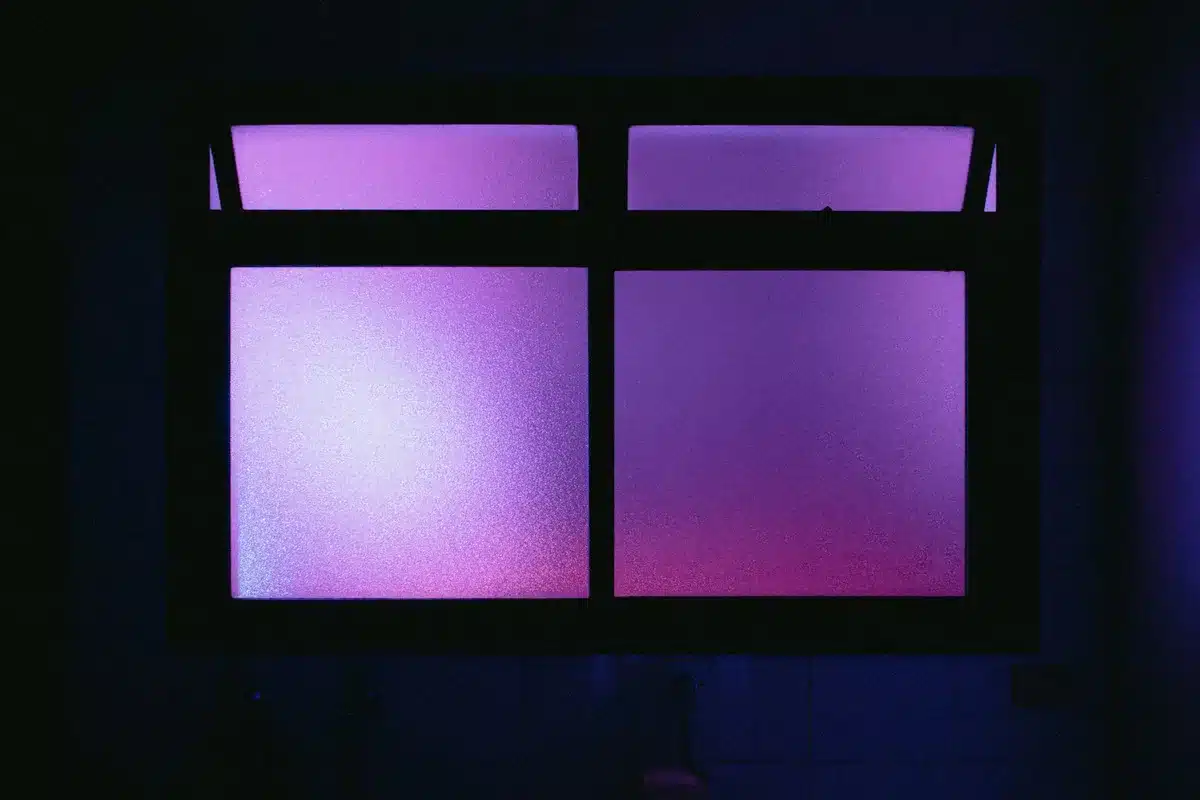 Interno minimalista con figura di spalle alla finestra, toni neutri e luce diffusa