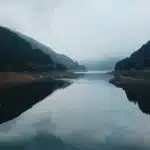 Paesaggio alpino simmetrico con montagne innevate riflesse in acque tranquille di un lago