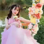 Bambina in vestito elegante con gonna voluminosa circondata da regali e luci natalizie