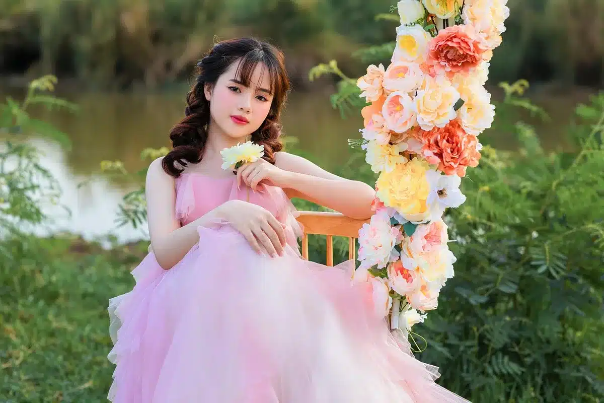 Bambina in vestito elegante con gonna voluminosa circondata da regali e luci natalizie