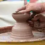 Mani anonime che lavorano fili di seta e piccoli attrezzi da oreficeria in un laboratorio
