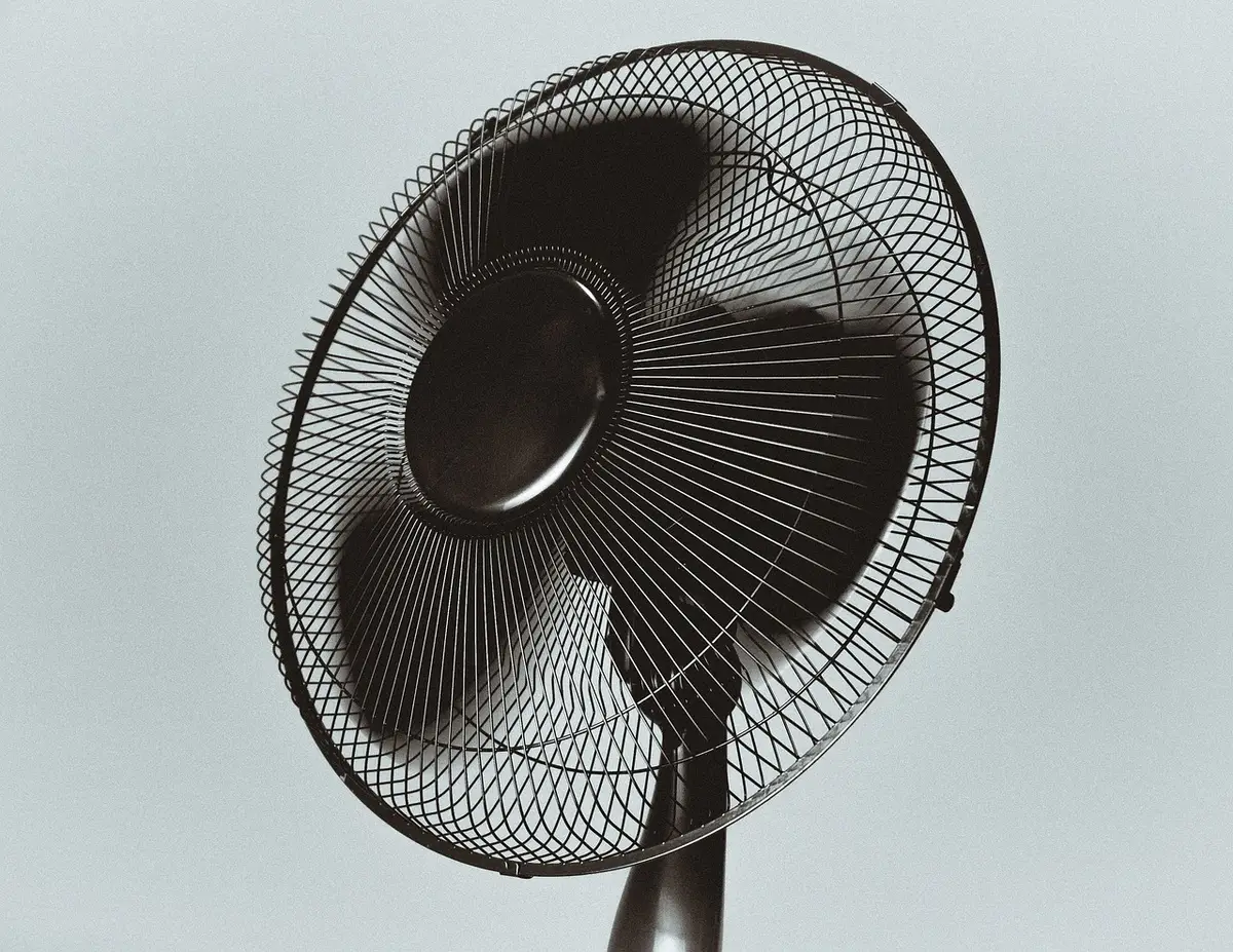 Ventilatore posizionato strategicamente in una stanza con finestre aperte per creare correnti d'aria