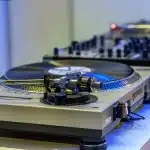 Silhouette di una consolle con vinili e la forma piramidale del club sullo sfondo